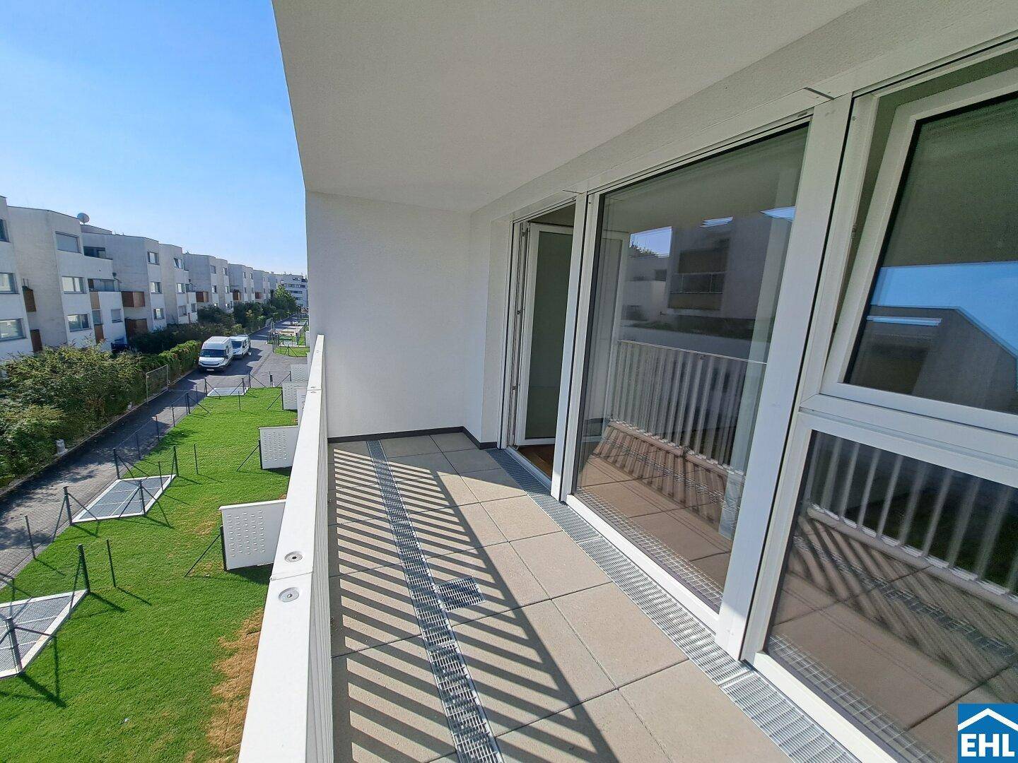 Geräumiger Balkon mit Fliesenboden und Blick auf die Umgebung und andere Gebäude.