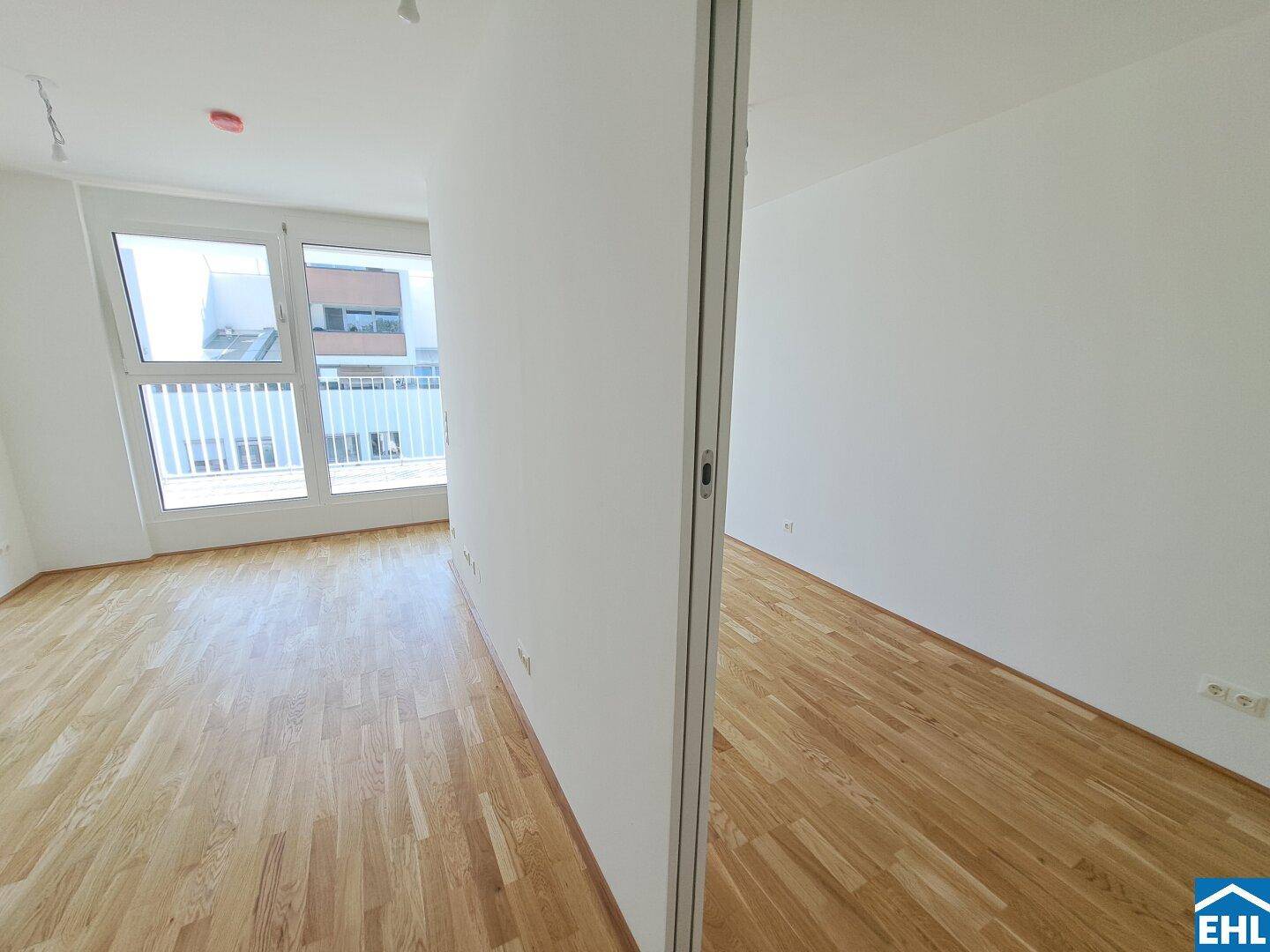 Heller Wohnraum mit Parkettboden, weißen Wänden und Zugang zum Außenbereich.