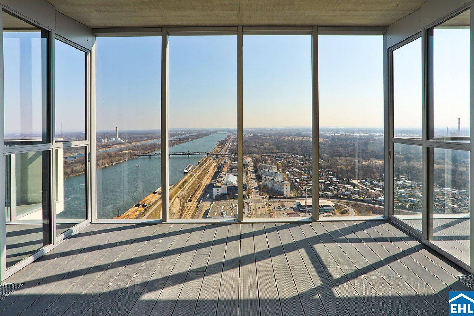 Offene Dachterrasse mit raumhohen Fenstern und weitem Blick über die Stadt und den Fluss.