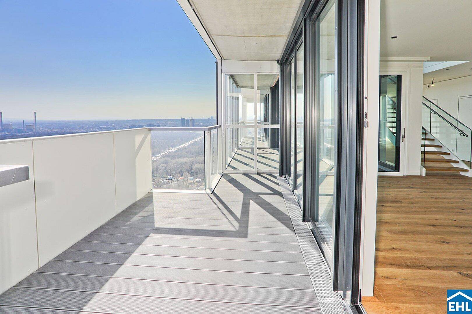 Langer Balkon mit Glasgeländer und weitem Blick über die Stadt und den Fluss.