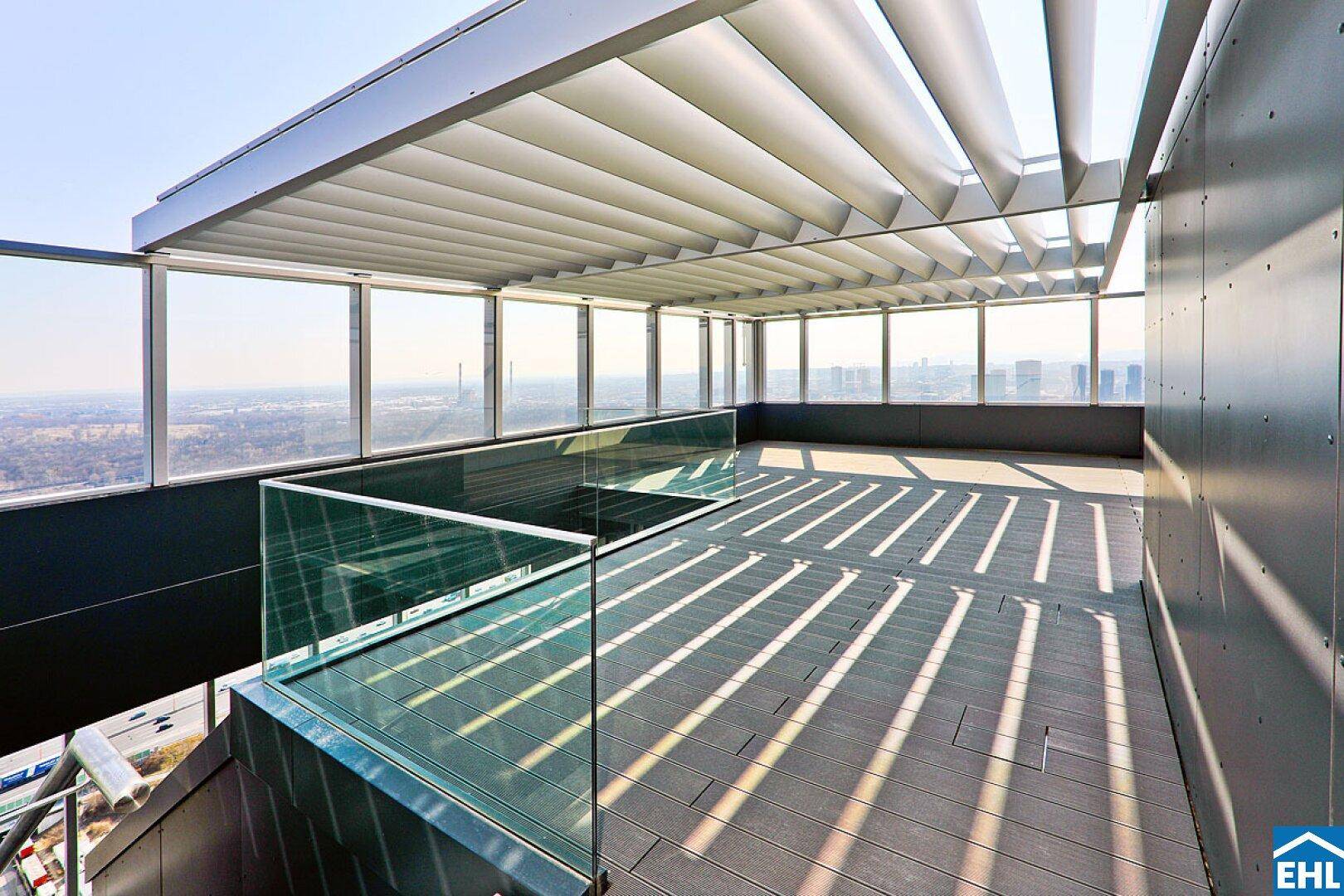 Moderne Dachterrasse mit Glasgeländer und beeindruckendem Ausblick auf die Umgebung.
