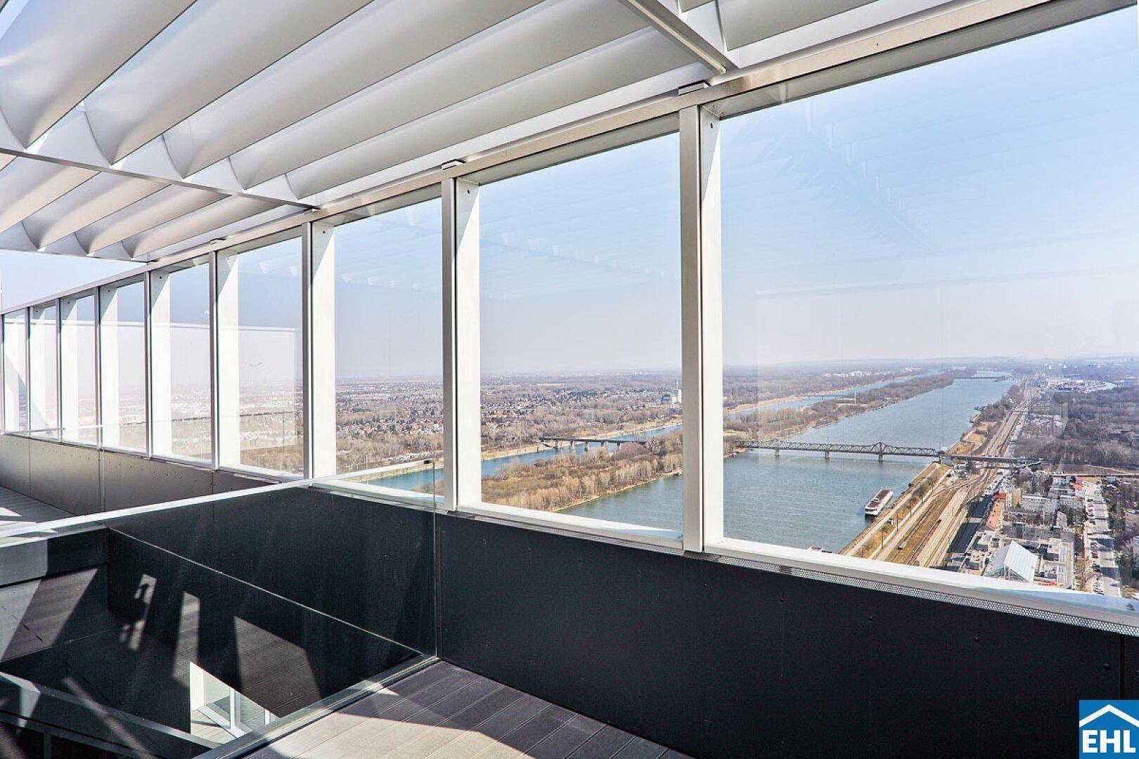 Weitläufiger Blick von der Dachterrasse über den Fluss und die Stadtlandschaft unter blauem Himmel.