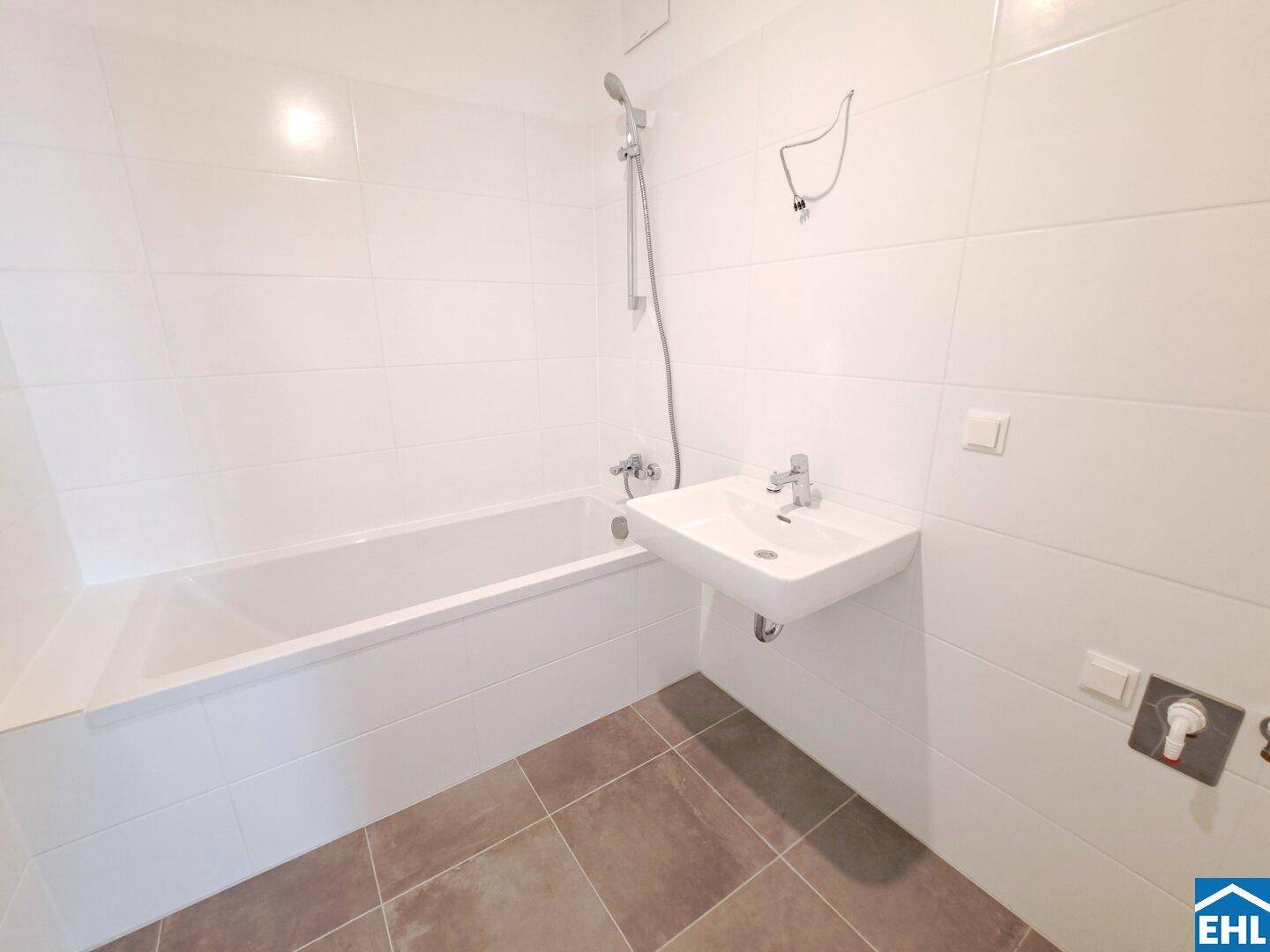 Modernes Badezimmer mit Badewanne, Waschbecken und weißen Wandfliesen sowie dunklem Boden.