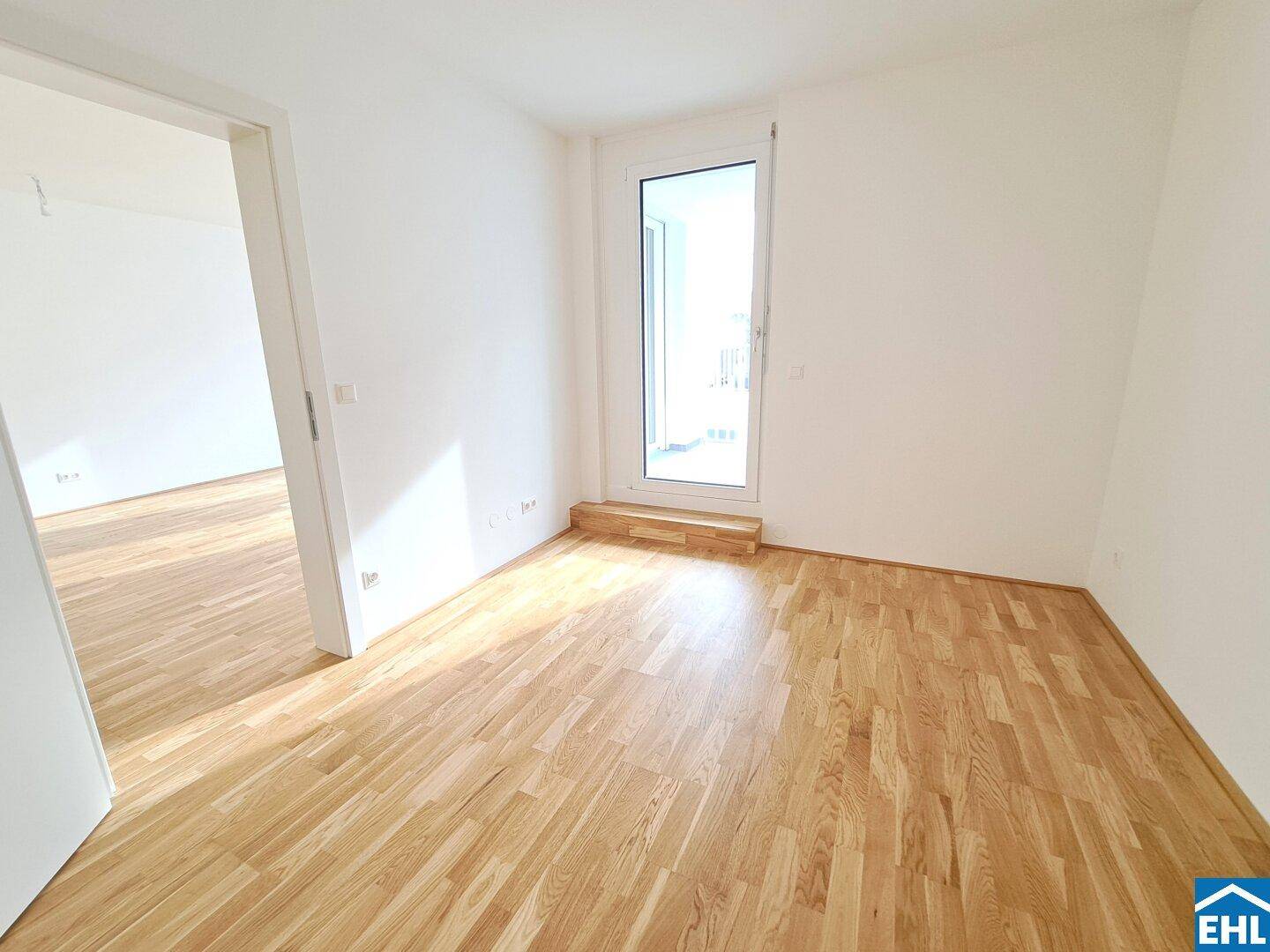 Helles Schlafzimmer mit Parkettboden und Zugang zu einem Balkon oder einer Terrasse.