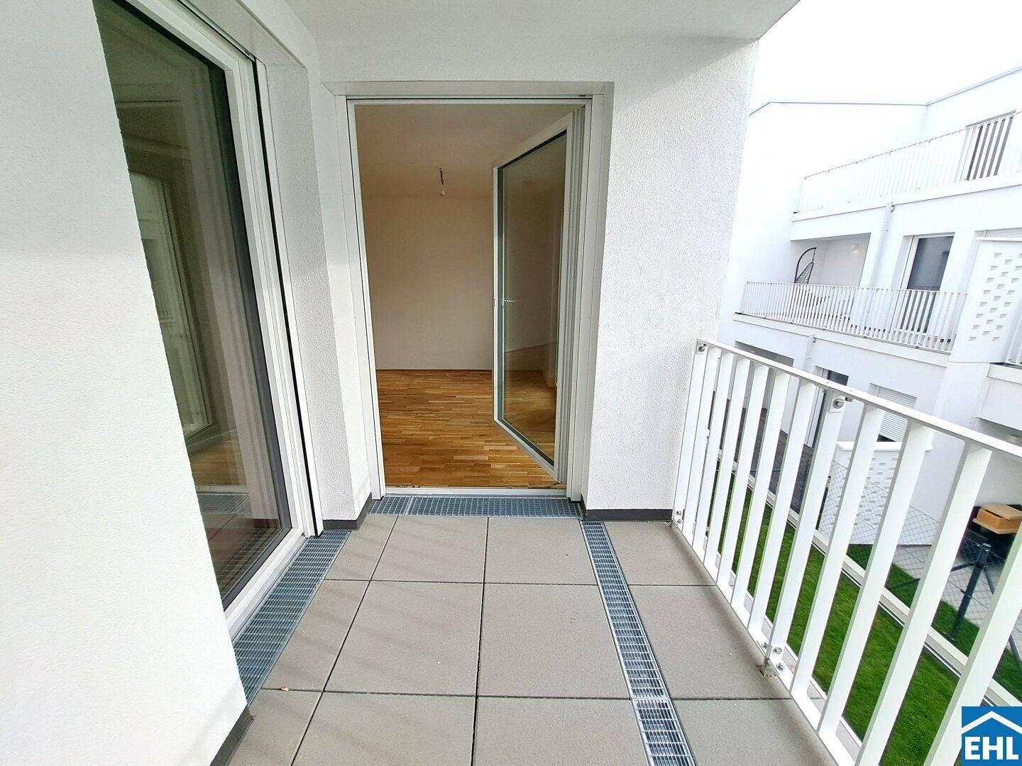Heller Balkon mit Fliesenboden und Blick in den Innenbereich der Wohnung.