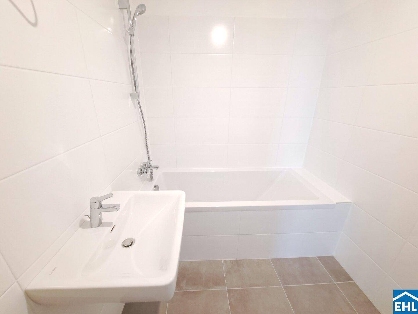 Modernes Badezimmer mit weißen Fliesen, Badewanne und Einzelwaschbecken.