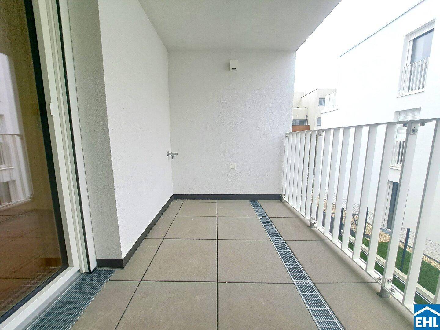 Geräumiger Balkon mit Fliesenboden und Blick auf die umliegenden Gebäude.