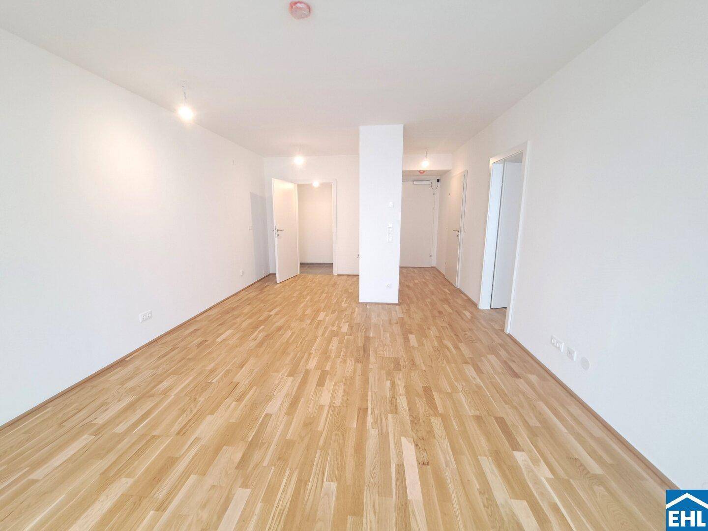 Geräumiger, heller Innenraum mit Holzboden und weiß gestrichenen Wänden.
