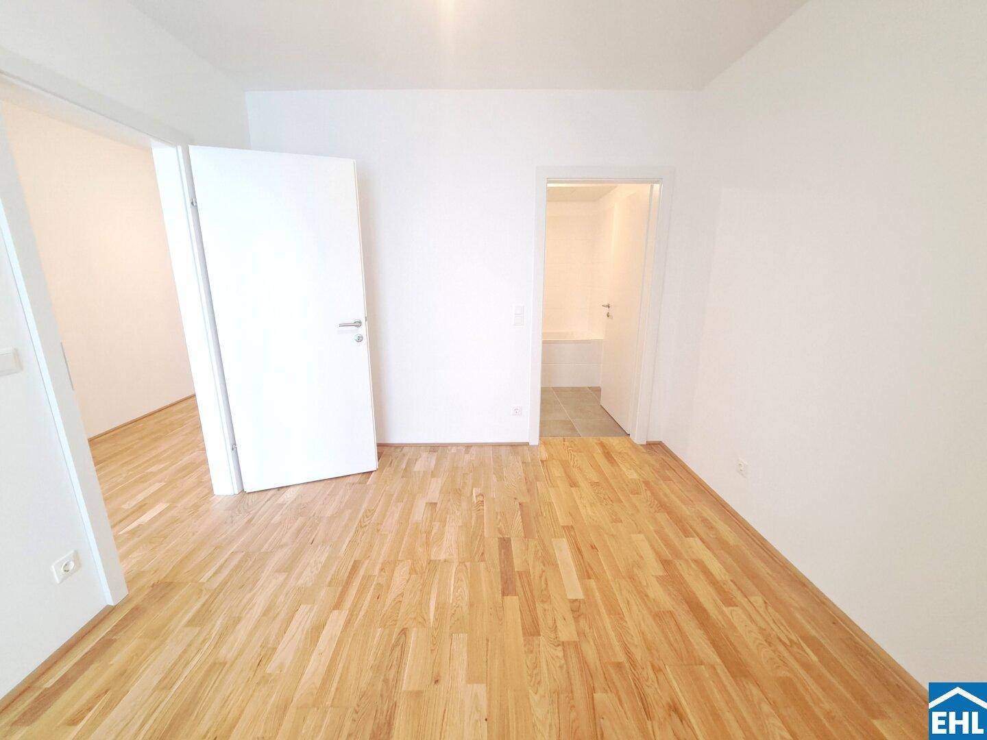 Schlafzimmer mit Parkettboden und direktem Zugang zu einem modernen Badezimmer.