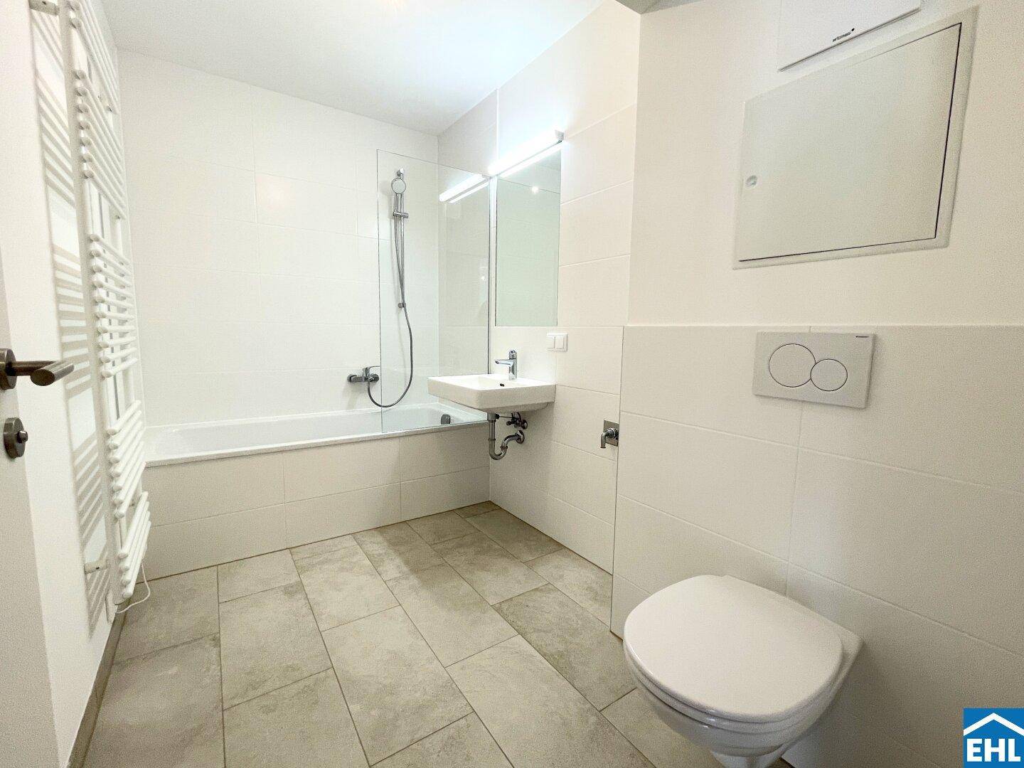 Modernes Badezimmer mit Badewanne, Dusche, wandhängendem WC und beheiztem Handtuchhalter.