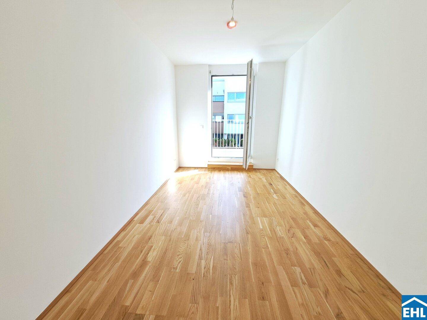 Heller, leerer Raum mit Holzboden und Zugang zu einem Balkon, ideal für Wohnzwecke.