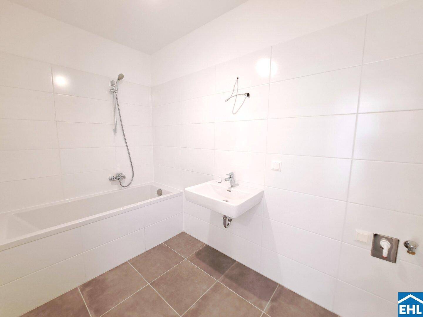 Modernes Badezimmer mit weißen Fliesen, Badewanne und einem einzelnen Waschbecken.