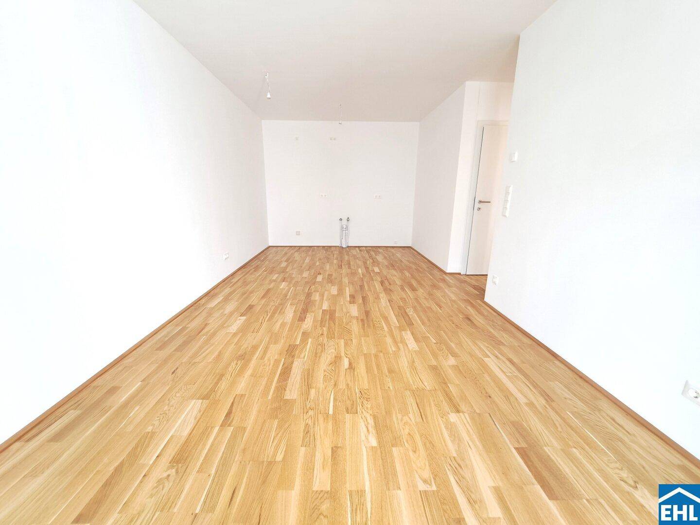 Heller, leerer Raum mit neuem Holzboden und weißen Wänden, bereit zur Einrichtung.