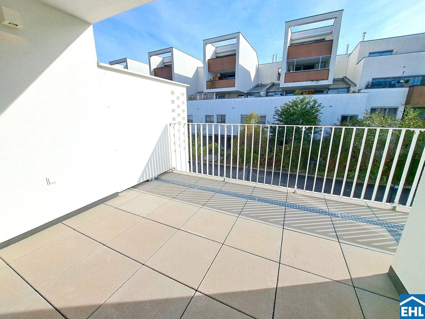 Geräumige Dachterrasse mit Fliesenboden und Blick auf moderne Wohngebäude.