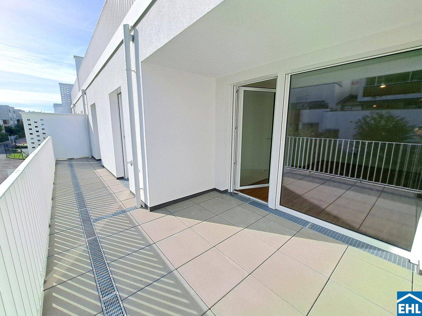 Große, sonnige Terrasse mit Zugang zum Innenbereich und Blick auf die Umgebung.