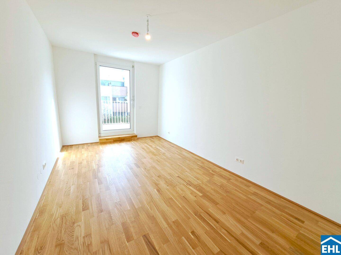 Helles Schlafzimmer mit Holzboden und Zugang zu einem französischen Balkon.
