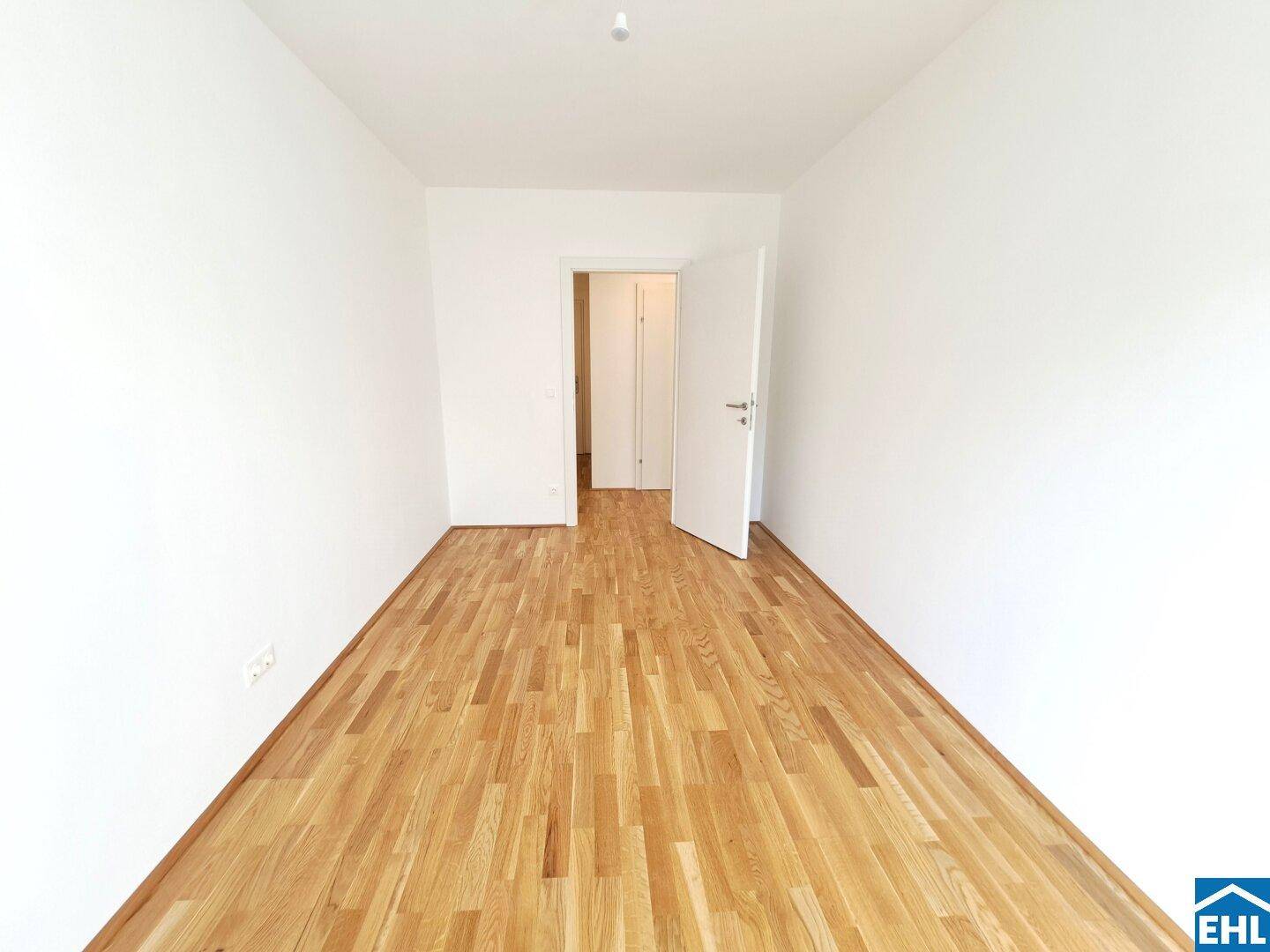 Leeres Schlafzimmer mit Holzboden und weiß gestrichenen Wänden, bereit zur Gestaltung.