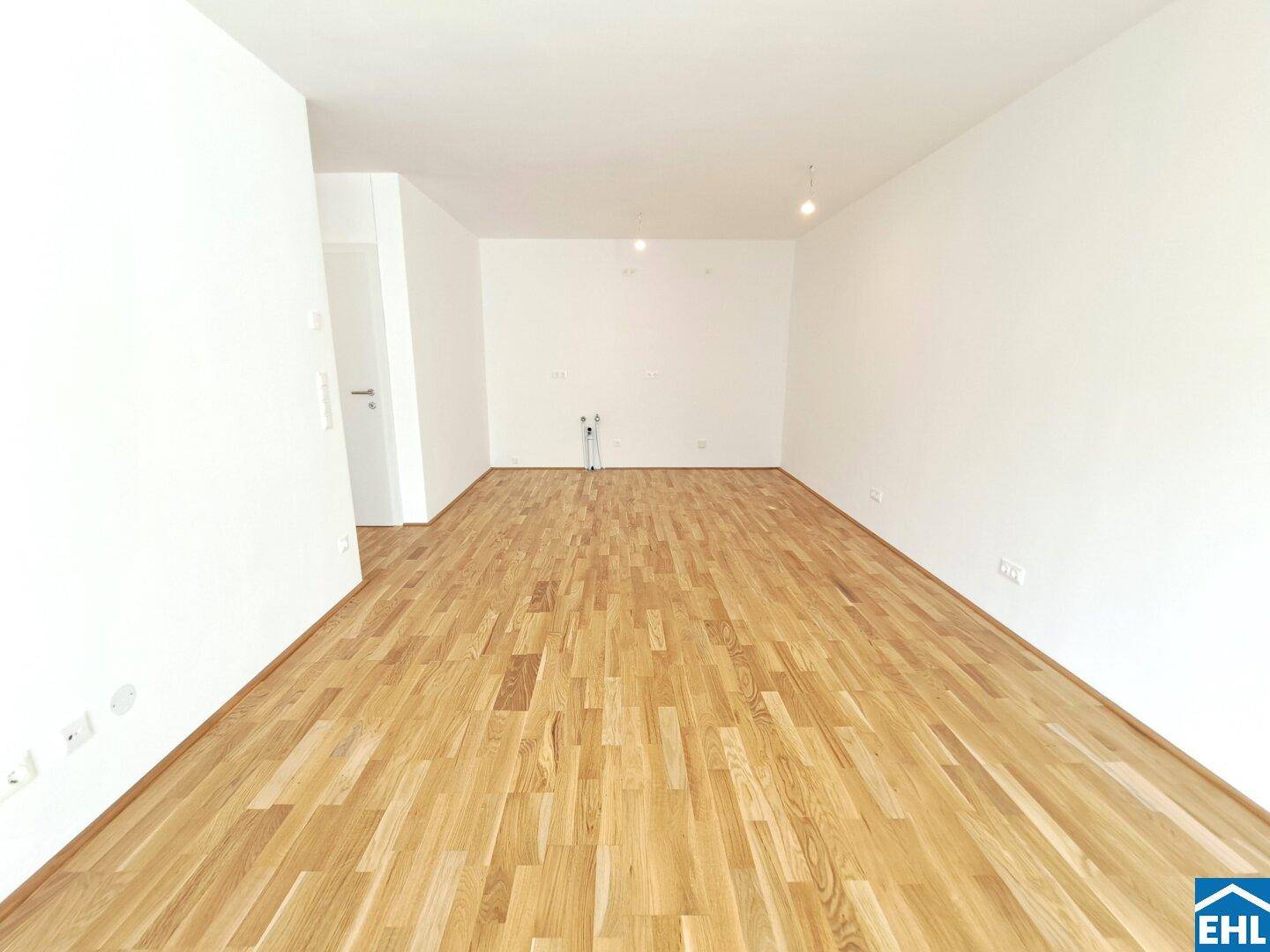 Leerer Raum mit hellem Holzboden und weißen Wänden, bereit für die Einrichtung.