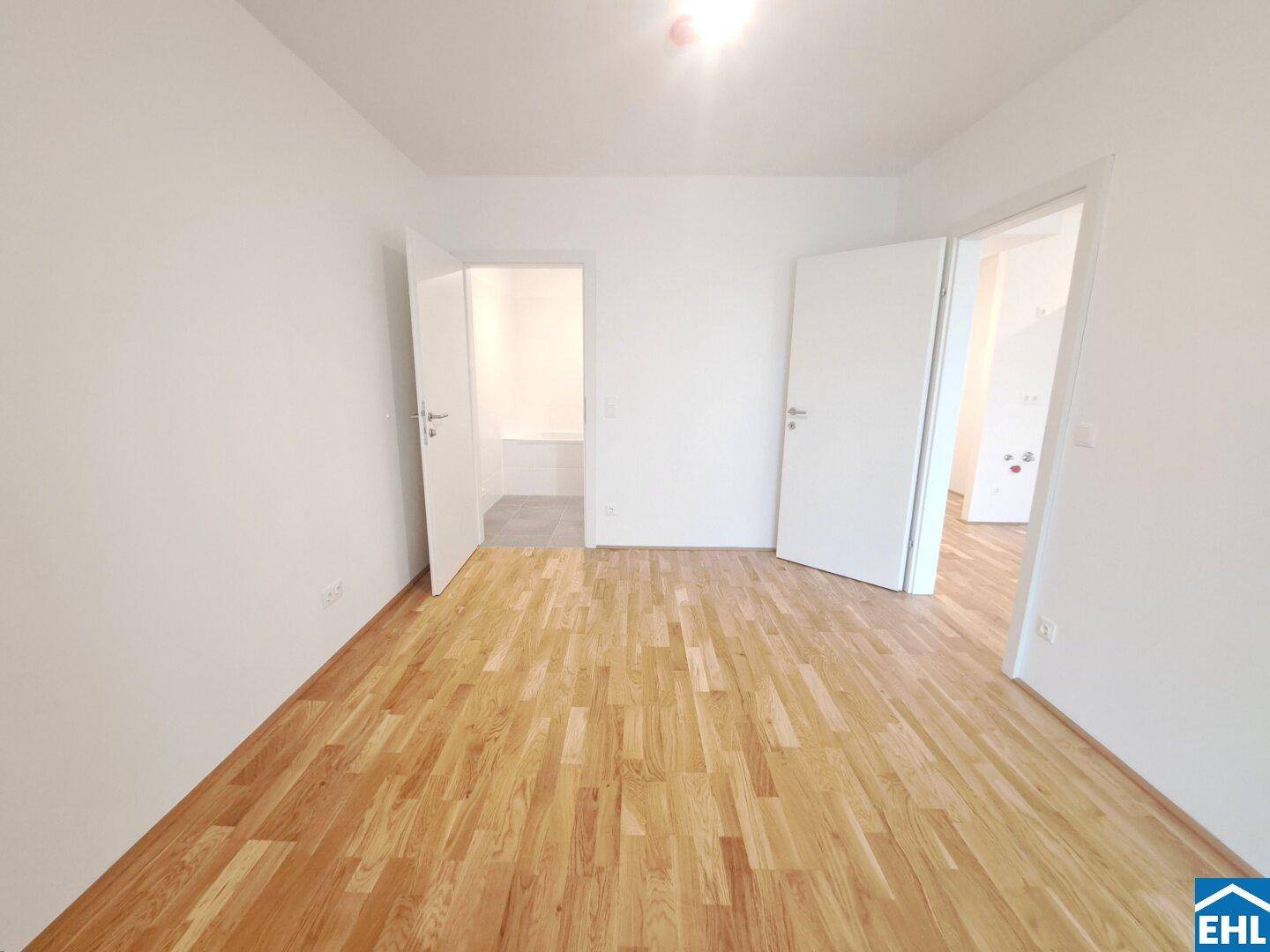 Helles Schlafzimmer mit Parkettboden und Zugang zu weiteren Räumen, ideal für individuelle Nutzung.