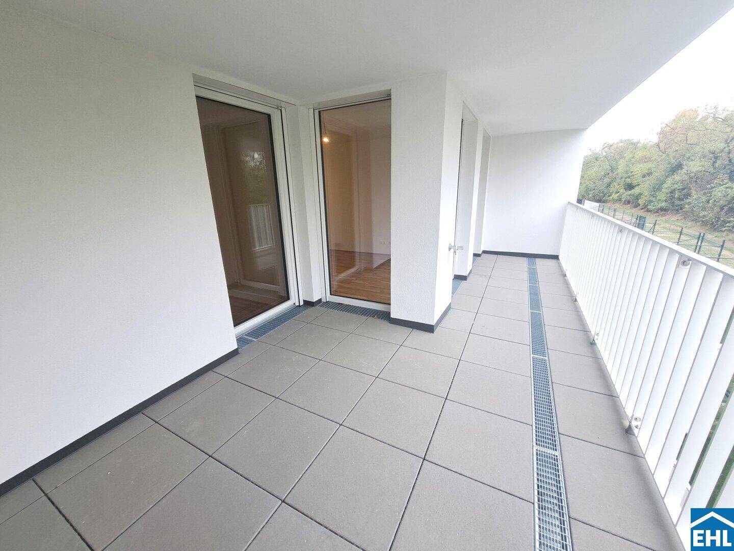 Langer Balkon mit Fliesenboden und Zugang zu Innenräumen, bietet Platz im Freien.