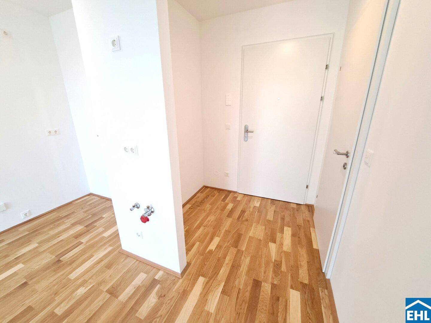 Ecke eines Raumes mit Parkettboden und sichtbaren Sanitäranschlüssen, ideal für eine Waschküche.
