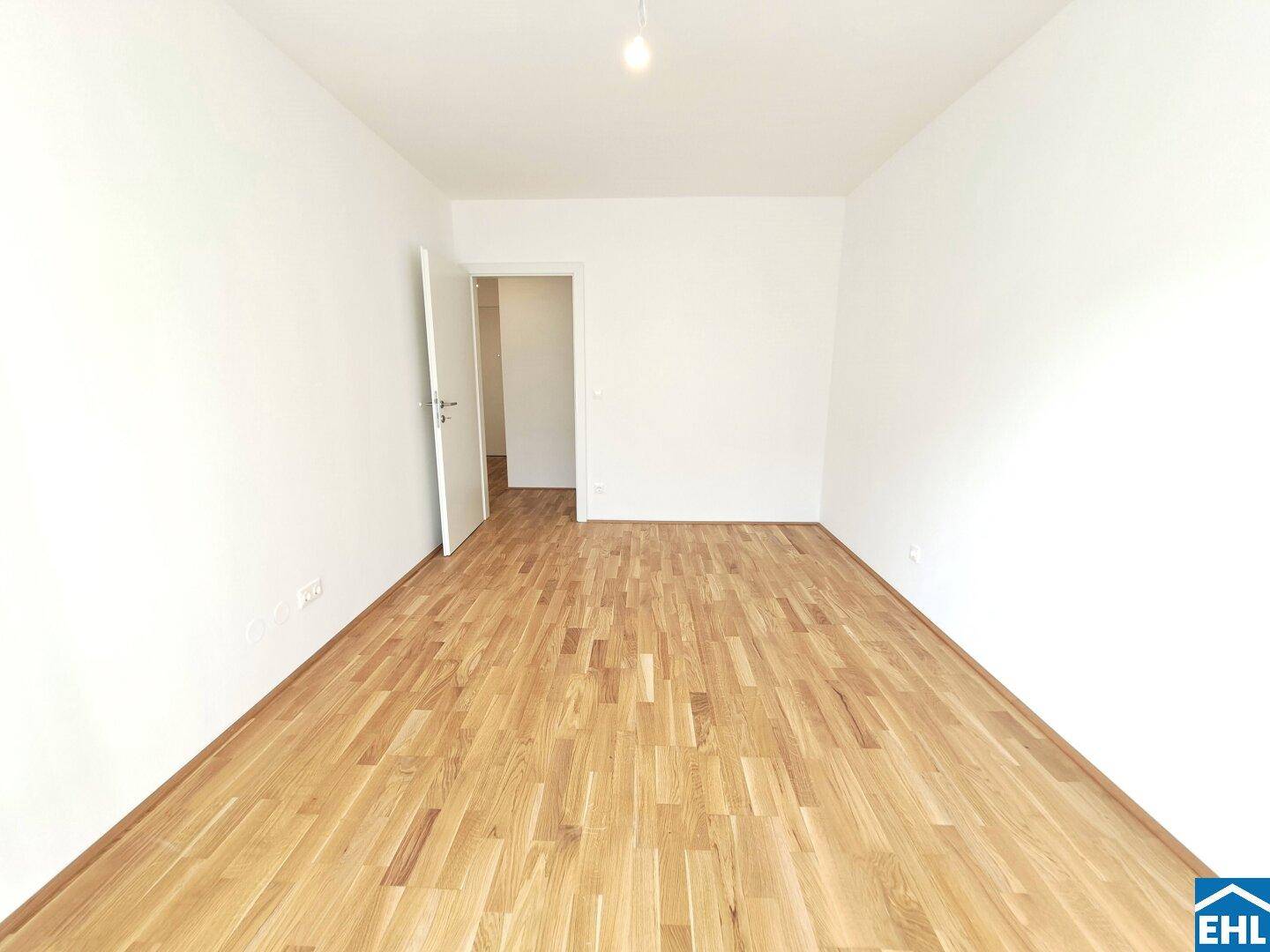 Leeres Zimmer mit hellem Parkettboden und weiß gestrichenen Wänden, bereit zur Einrichtung.