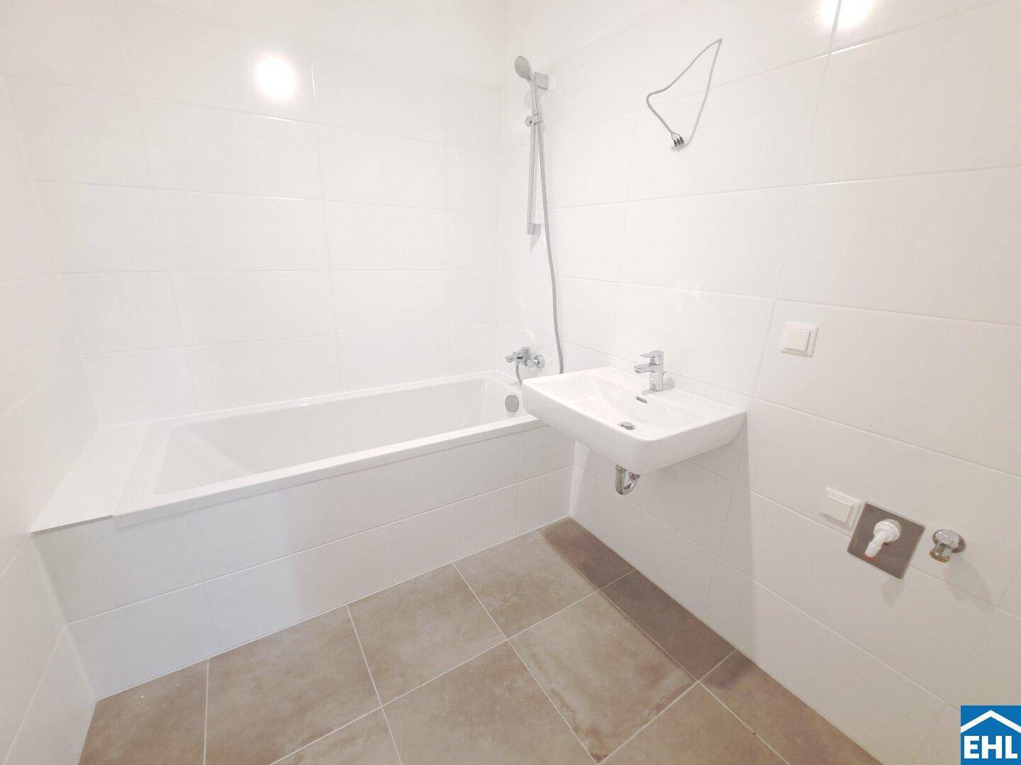 Modernes Badezimmer mit weißen Fliesen, Badewanne mit Duschfunktion und Einzelwaschbecken.
