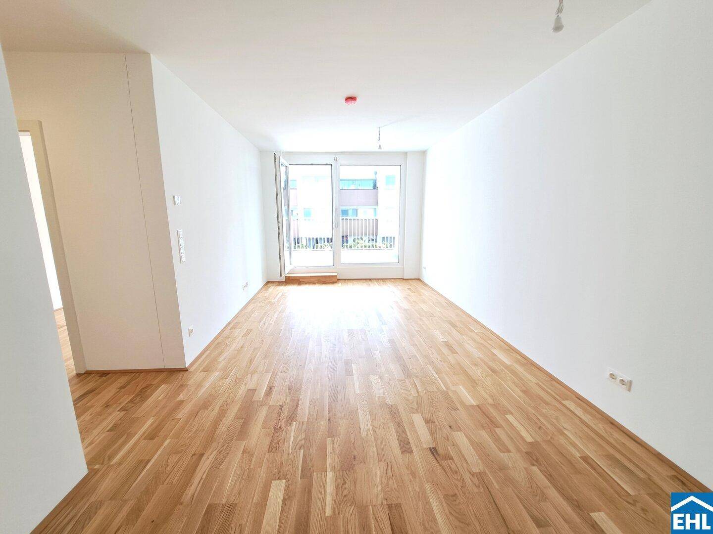 Lichtdurchflutetes Wohnzimmer mit hellem Eichenparkett und Zugang zum Außenbereich.