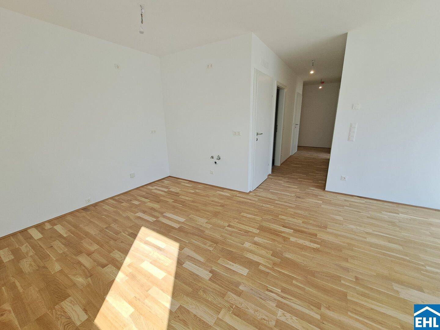 Langer, heller Flur mit Holzboden, der zu weiteren Räumen in der Wohnung führt.