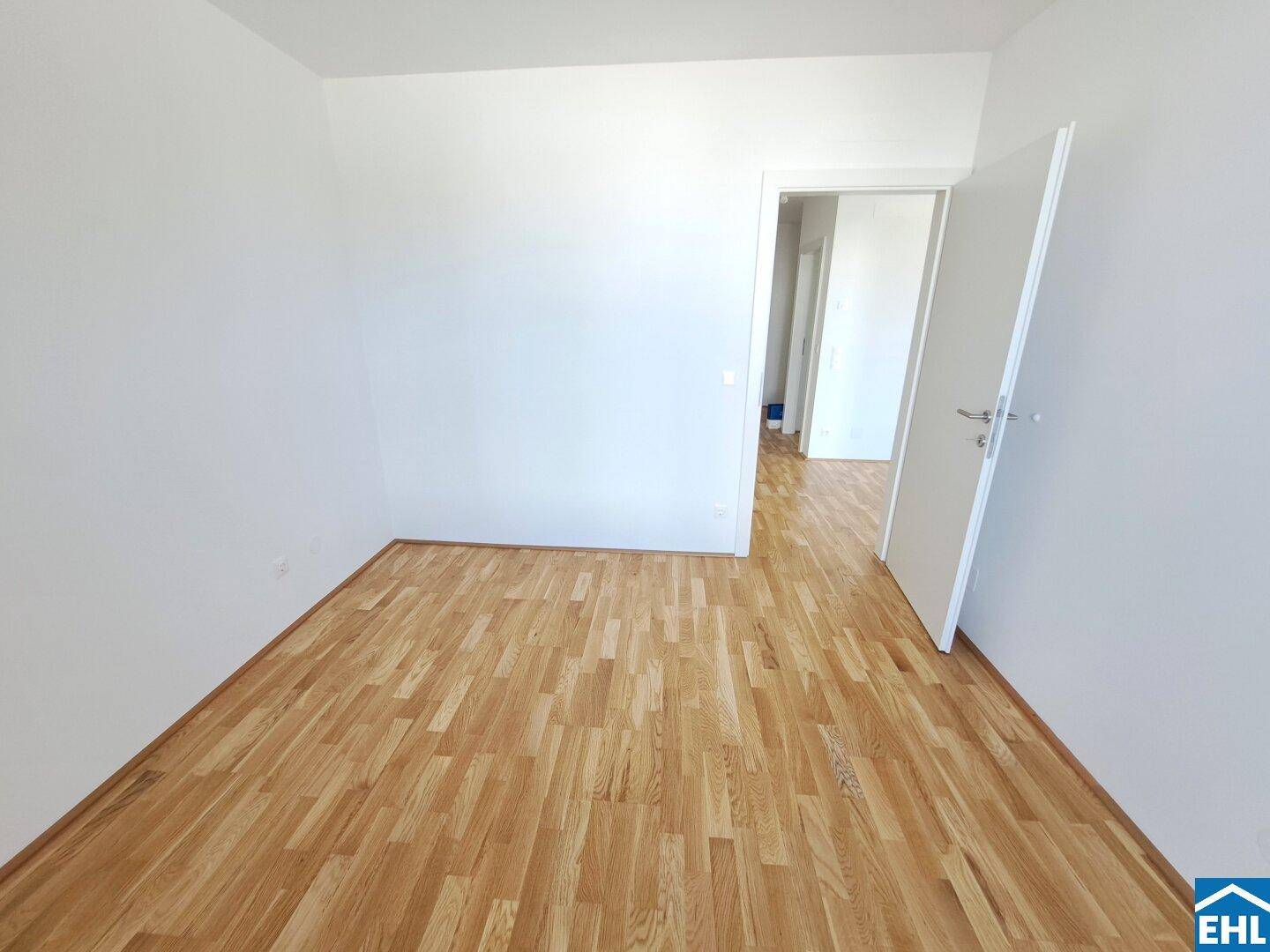Leeres Schlafzimmer mit Parkettboden und weiß gestrichenen Wänden, bereit zur individuellen Gestaltung.