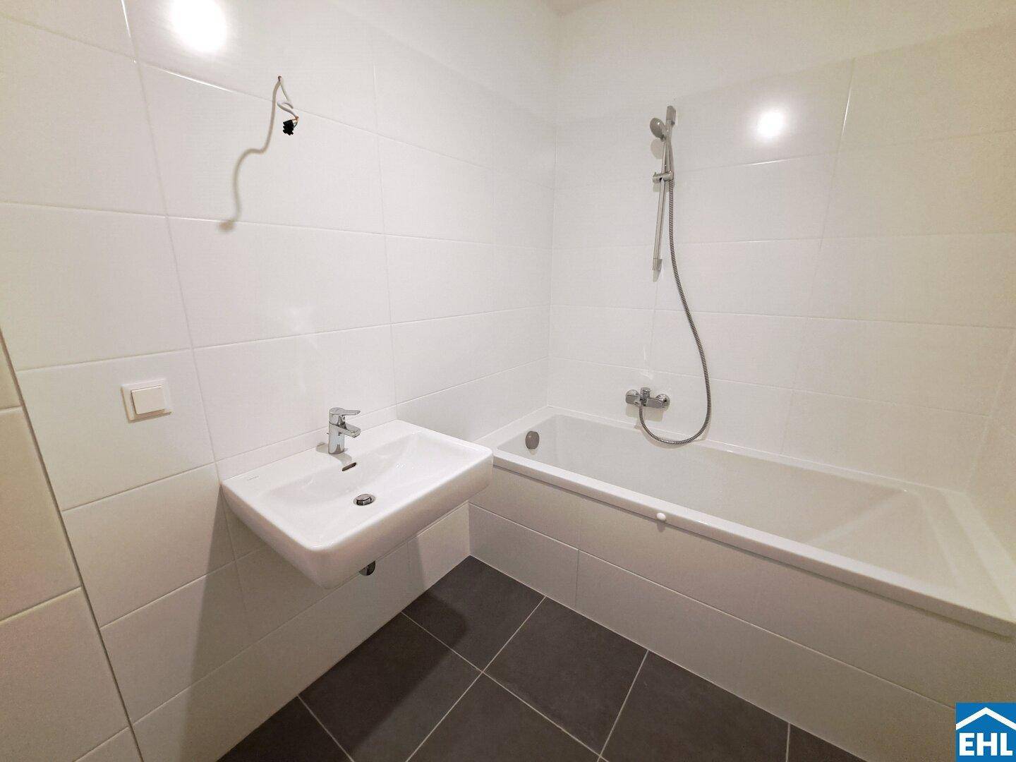 Modernes Badezimmer mit weißen Fliesen, Badewanne und einem einzelnen Waschbecken.