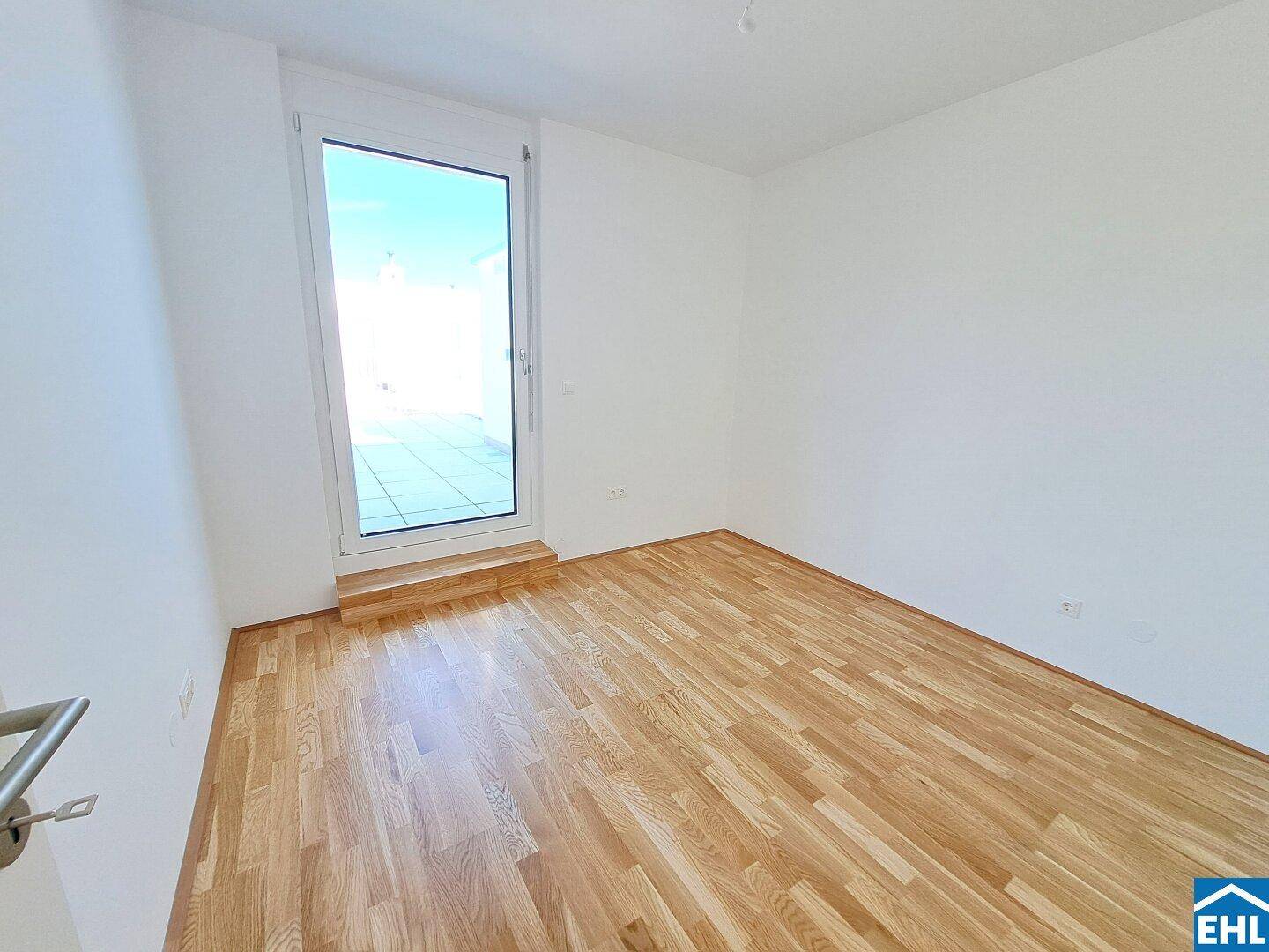 Helles Schlafzimmer mit Parkettboden und direktem Zugang zu einer Terrasse oder einem Balkon.