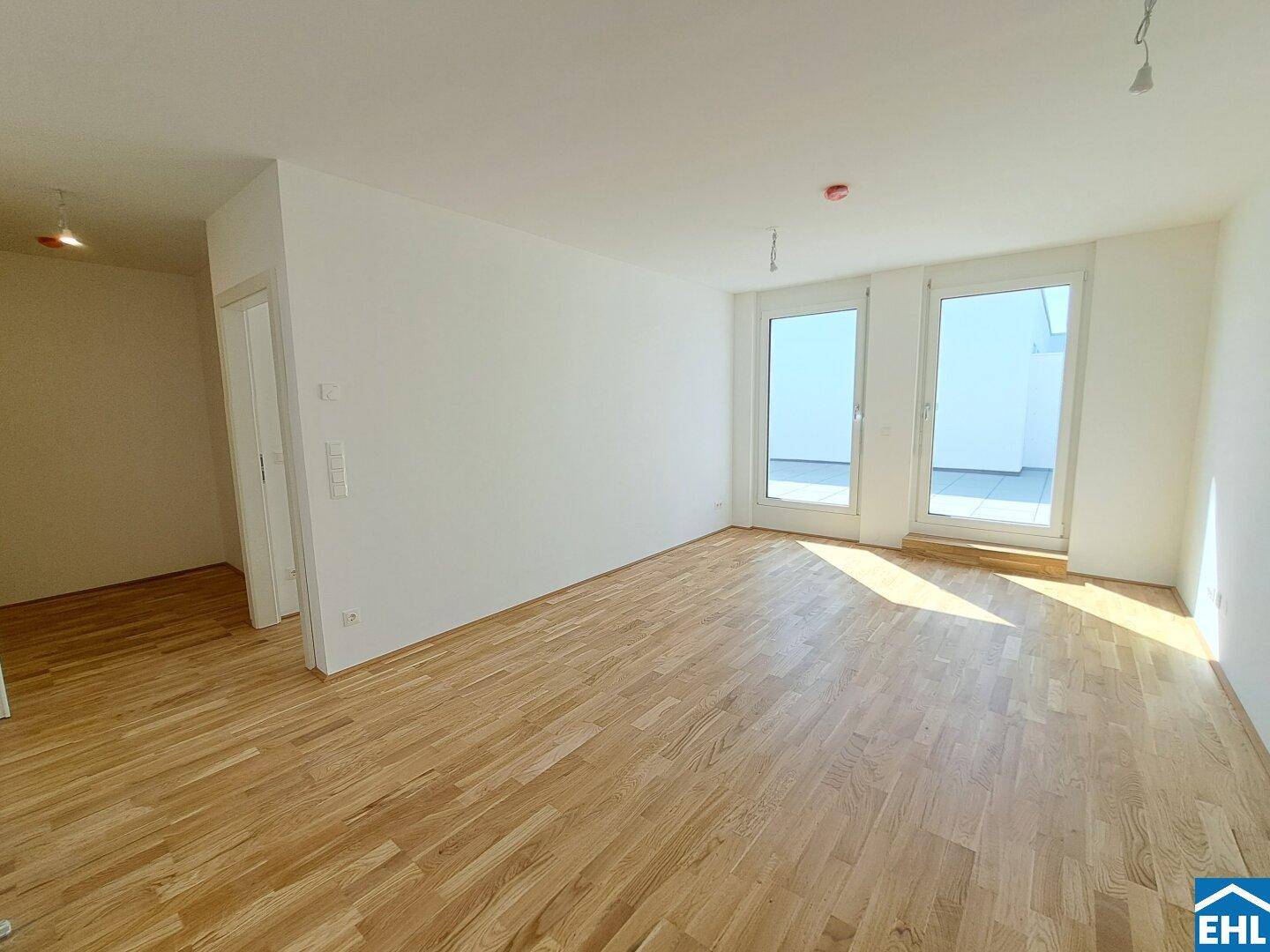 Lichtdurchfluteter Wohnbereich mit hellem Parkettboden und direktem Terrassenzugang.