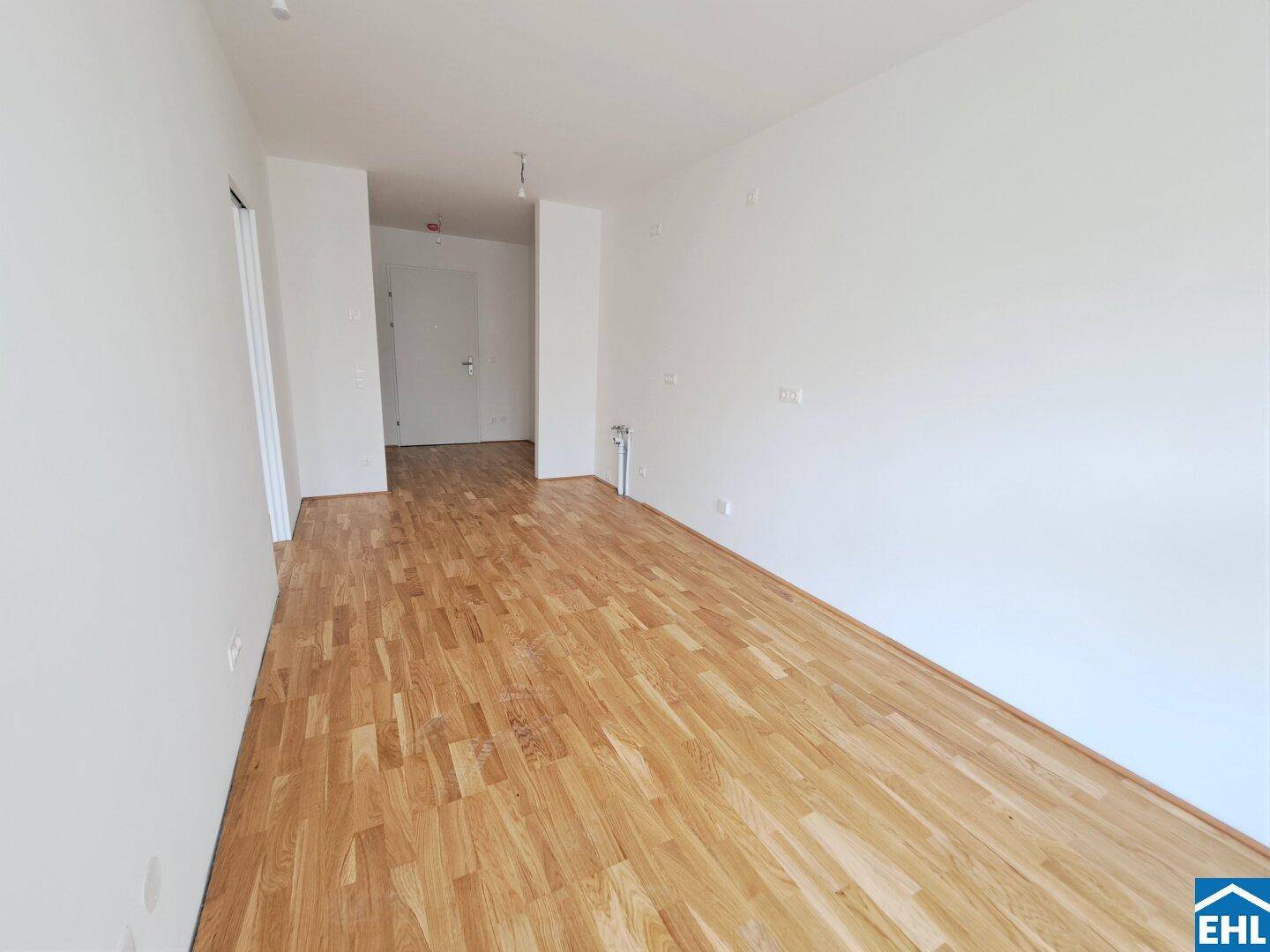 Geräumiger, heller Wohnbereich mit hochwertigem Parkettboden und weiß gestrichenen Wänden.
