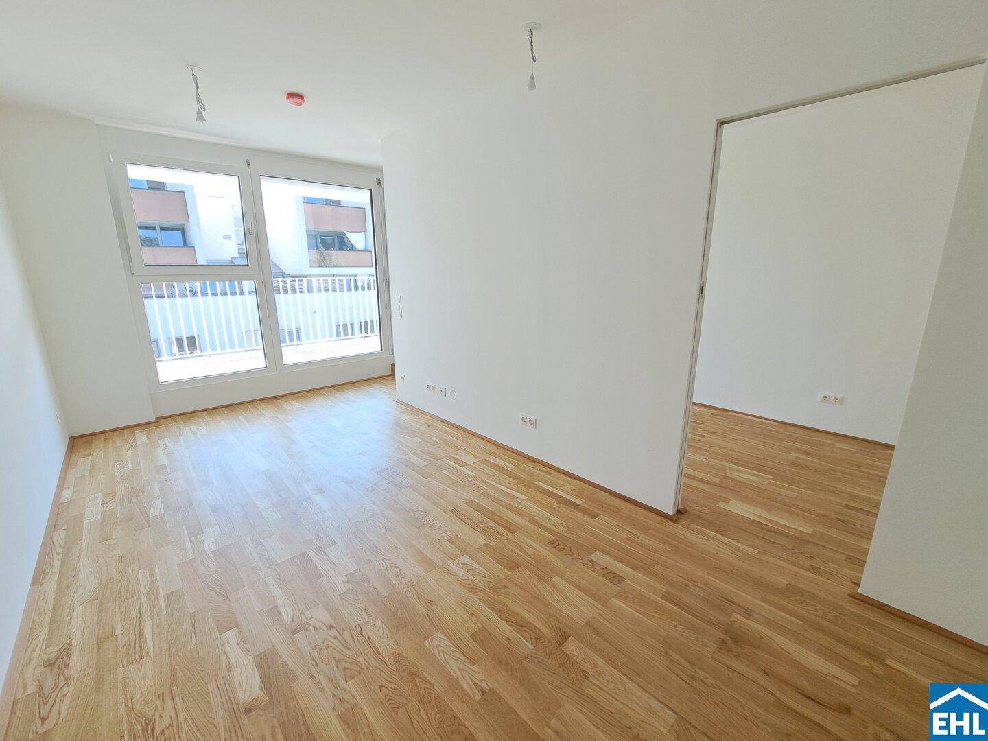 Heller Wohnraum mit Parkettboden und Zugang zu einem Balkon, ideal für modernes Wohnen.