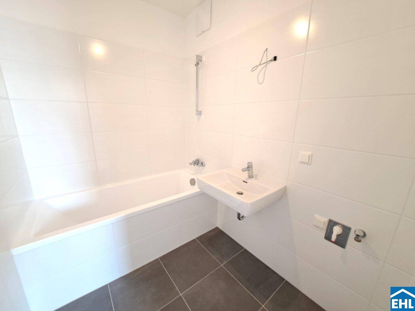 Modernes Badezimmer mit weiß gefliesten Wänden, Badewanne und Waschbecken.