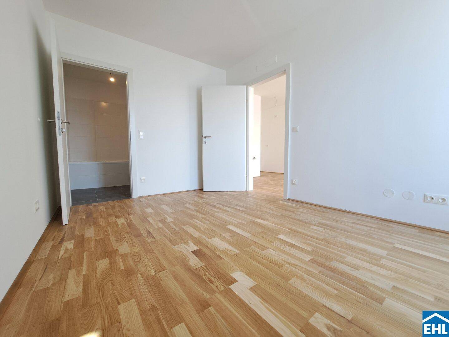 Heller Flur mit Parkettboden und Zugang zu verschiedenen Zimmern, inklusive Badezimmer.