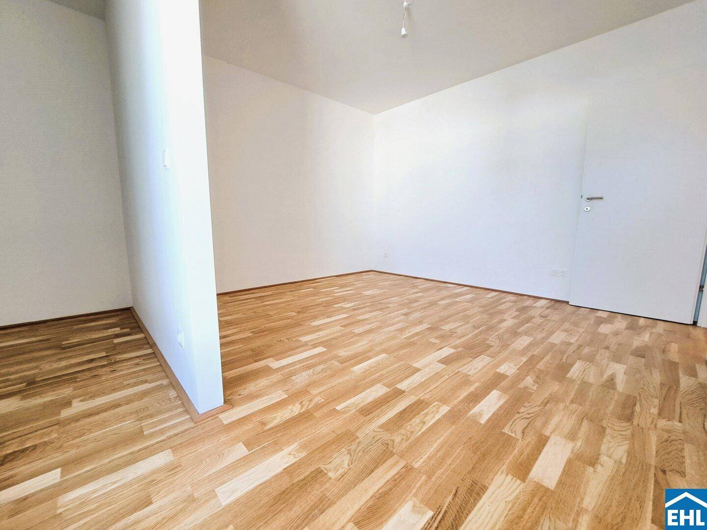 Leerer Raum mit hellem Parkettboden und weiß gestrichenen Wänden, bietet vielseitige Gestaltungsmöglichkeiten.