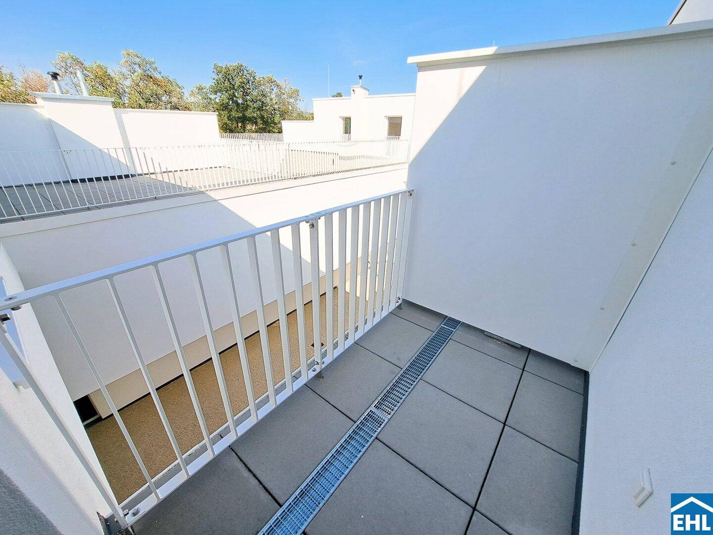 Kleiner, sonniger Balkon mit Fliesenboden und weißem Geländer, ideal für entspannte Stunden.