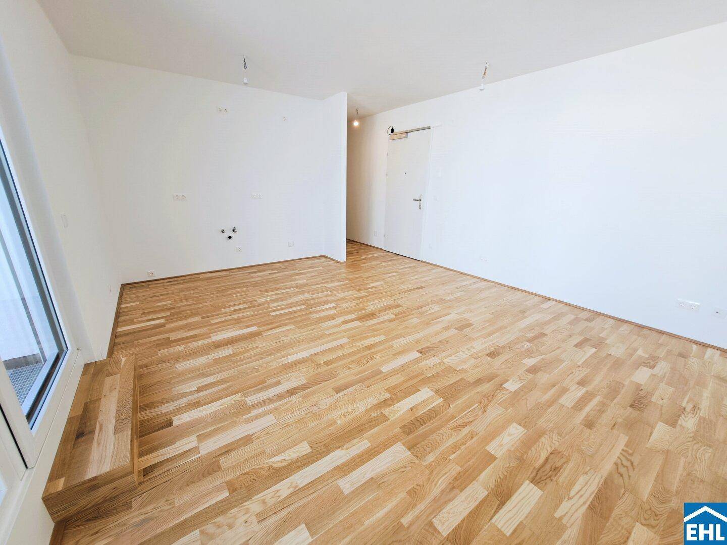 Geräumiges, leeres Zimmer mit hellem Parkettboden und weiß gestrichenen Wänden, bereit zur Einrichtung.