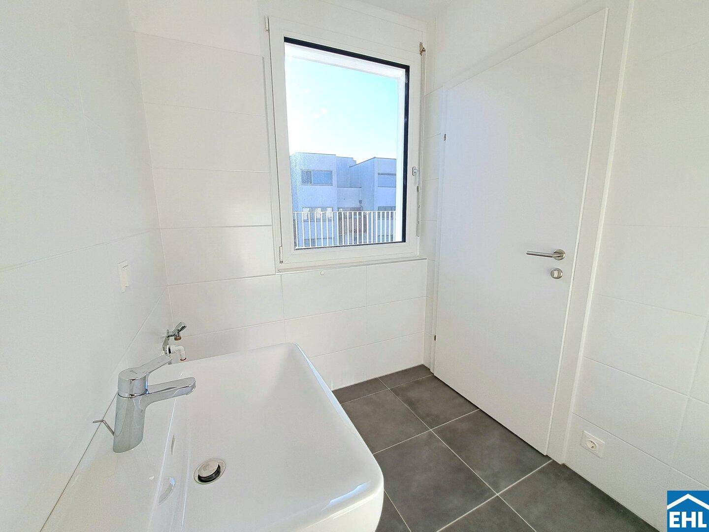 Modernes Gäste-WC mit Waschbecken, Fenster und hellen Fliesen an Wänden und Boden.