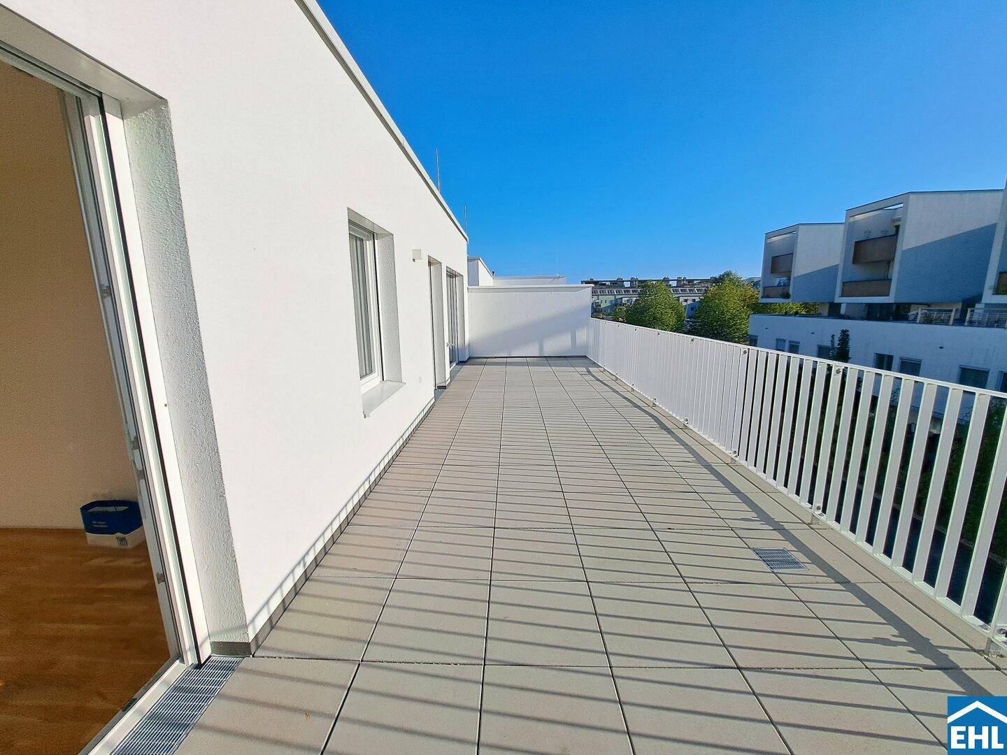 Weitläufige Terrasse mit moderner Brüstung und viel Platz im Freien unter blauem Himmel.