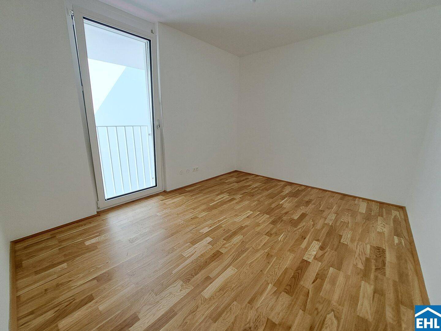 Helles Schlafzimmer mit Holzboden und Zugang zu einem kleinen Außenbereich.