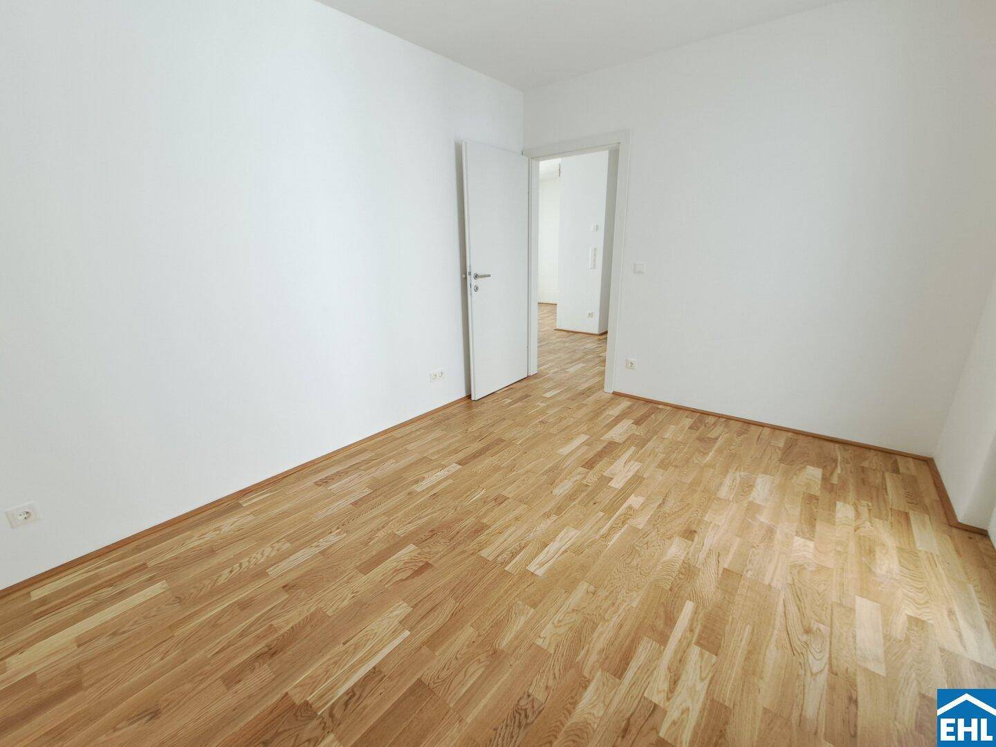 Leeres Schlafzimmer mit hellem Parkettboden und weißen Wänden, bereit zur Einrichtung.