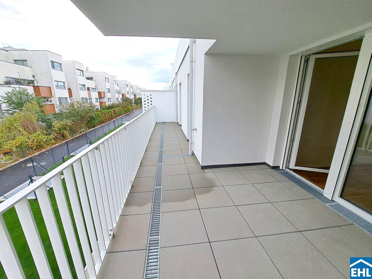 Langer Balkon mit Fliesenboden und weißem Geländer, bietet einen Blick auf die Umgebung.
