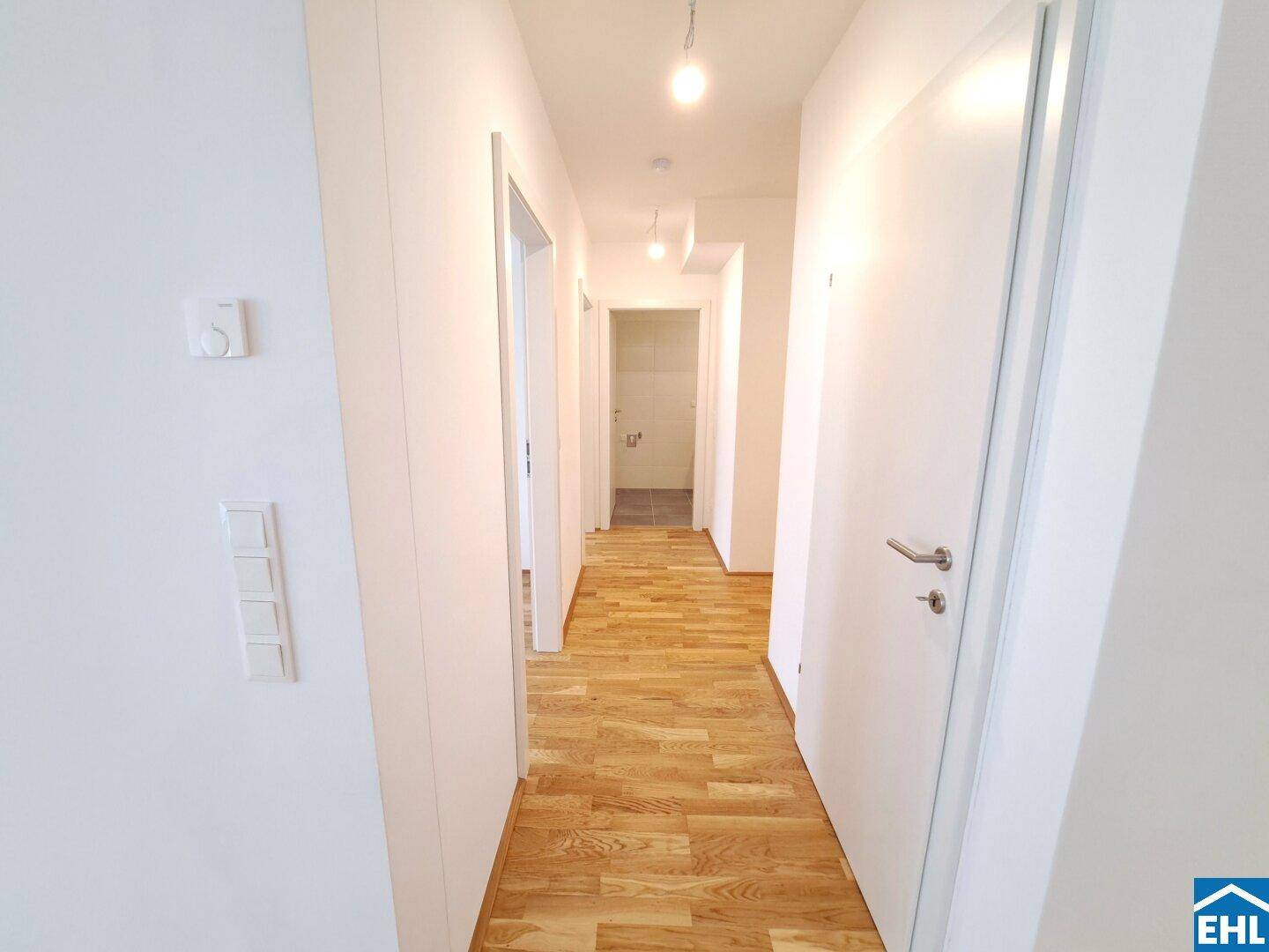 Langer, heller Flur mit Parkettboden, der zu verschiedenen Räumen der Wohnung führt.