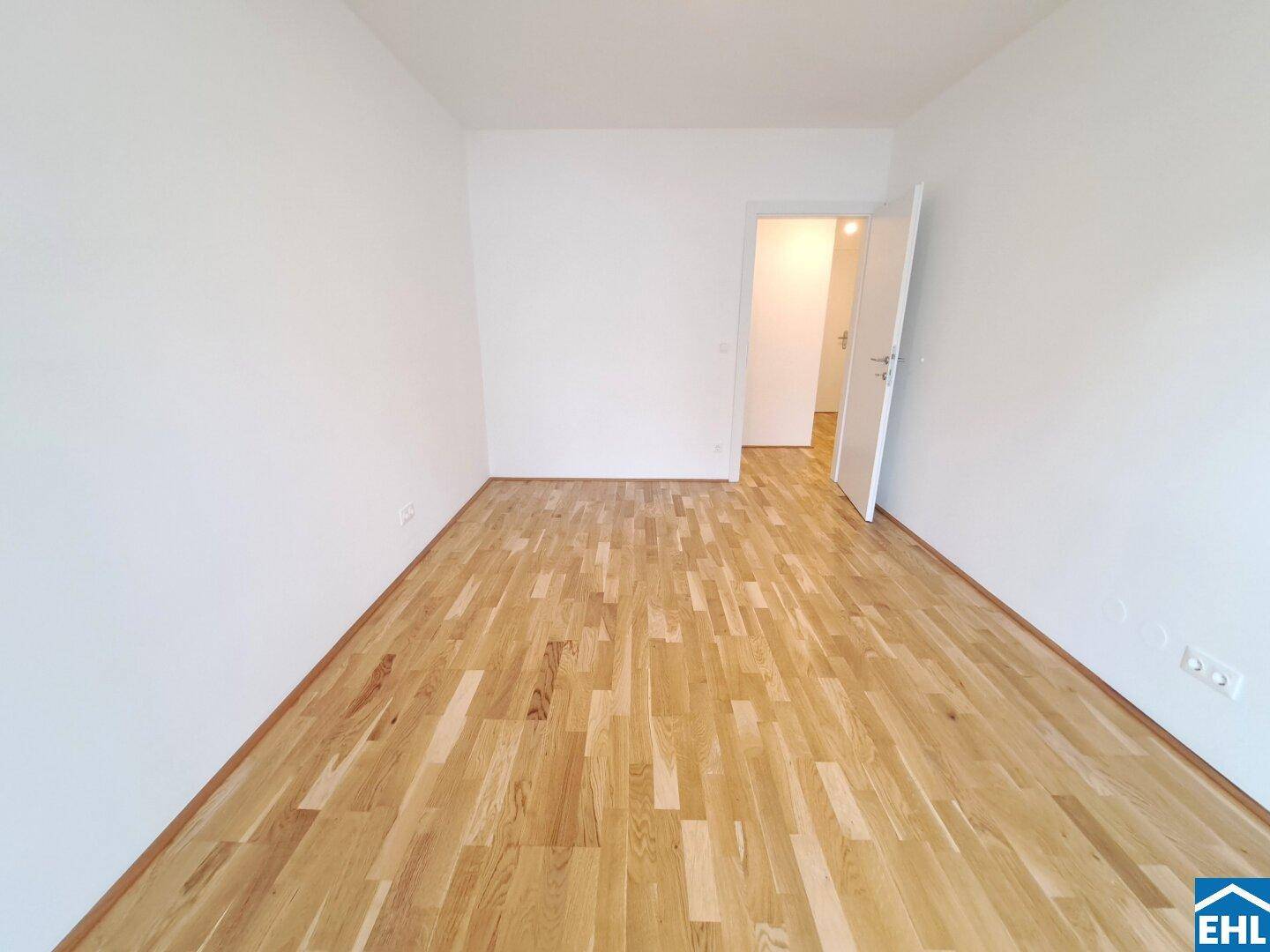 Helles Schlafzimmer mit neuem Parkettboden und weiß gestrichenen Wänden, bereit zum Einzug.
