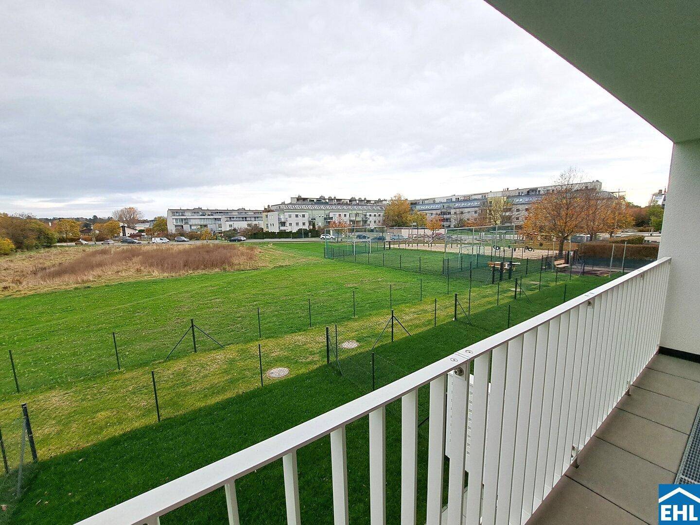 Weitläufiger Blick vom Balkon über eine große Grünfläche und die umliegende Bebauung.
