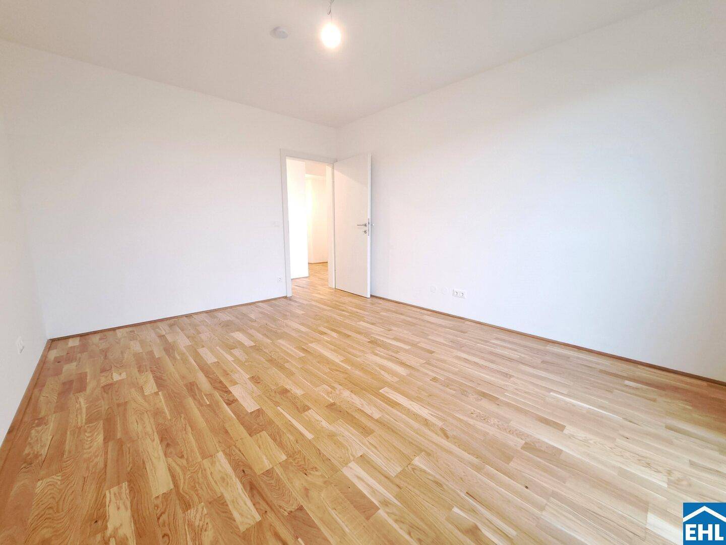 Helles Schlafzimmer mit Holzboden und weiß gestrichenen Wänden, bereit zur individuellen Gestaltung.