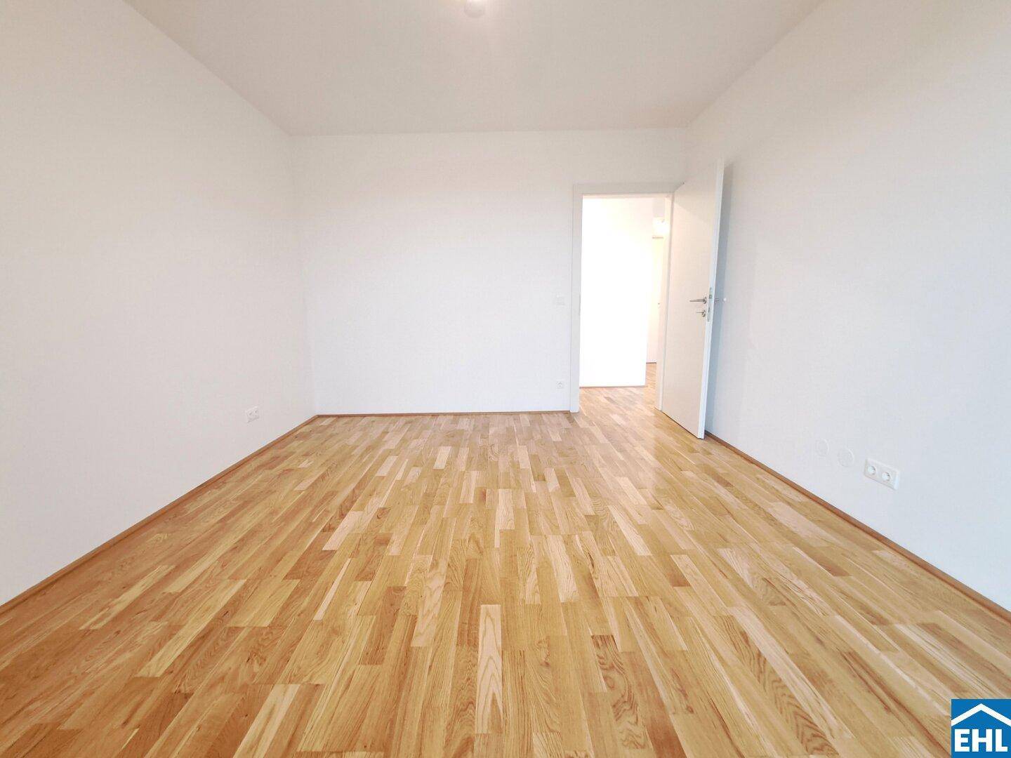 Geräumiges Zimmer mit Parkettboden und weißer Wandgestaltung, ideal für ein Schlafzimmer.